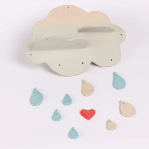 Mobile décoratif en céramique en forme de nuage, avec des gouttes colorées et un petit cœur rouge, création artisanale lors d’un atelier