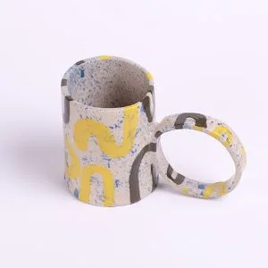 Tasse en céramique peinte à l’engobe avec motifs jaunes et bleus, anse ronde originale façonnée à la main.
