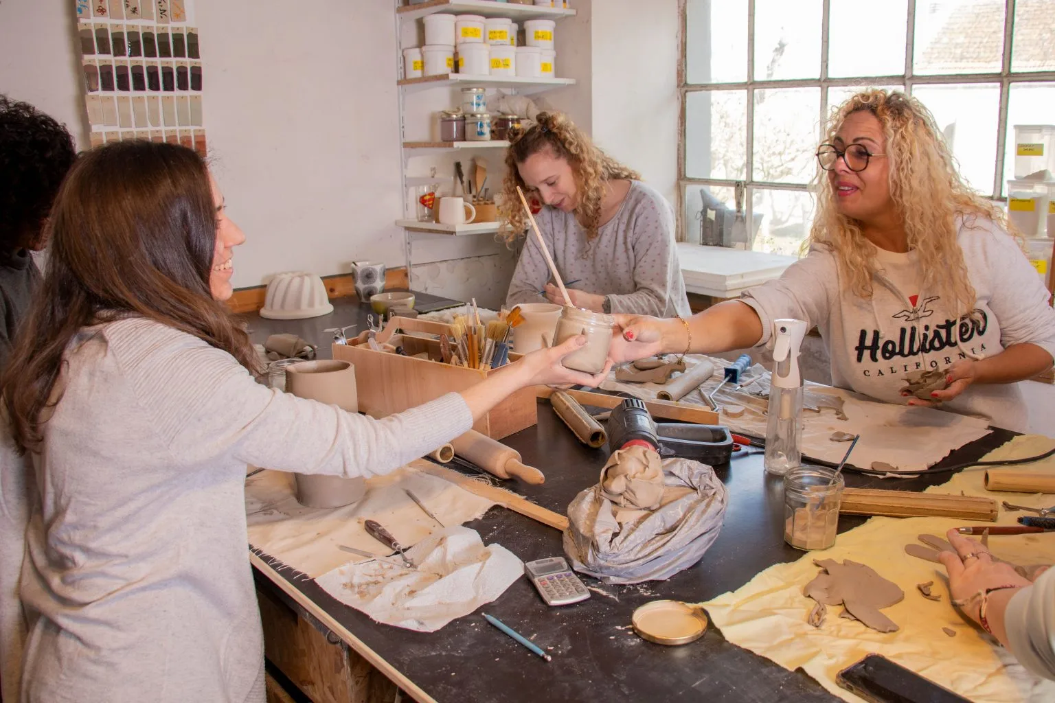 Participants souriants travaillant ensemble à l’atelier de poterie, créant dans la bonne humeur et la convivialité