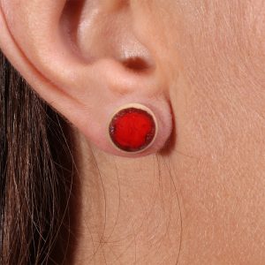 Gros plan sur la boucle d’oreille puce Lueur de Braise Rouge Feu en porcelaine, détail du rouge intense et de l’émail.