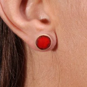 Gros plan sur la boucle d’oreille puce Lueur de Braise Rouge Feu en porcelaine, détail du rouge intense et de l’émail.