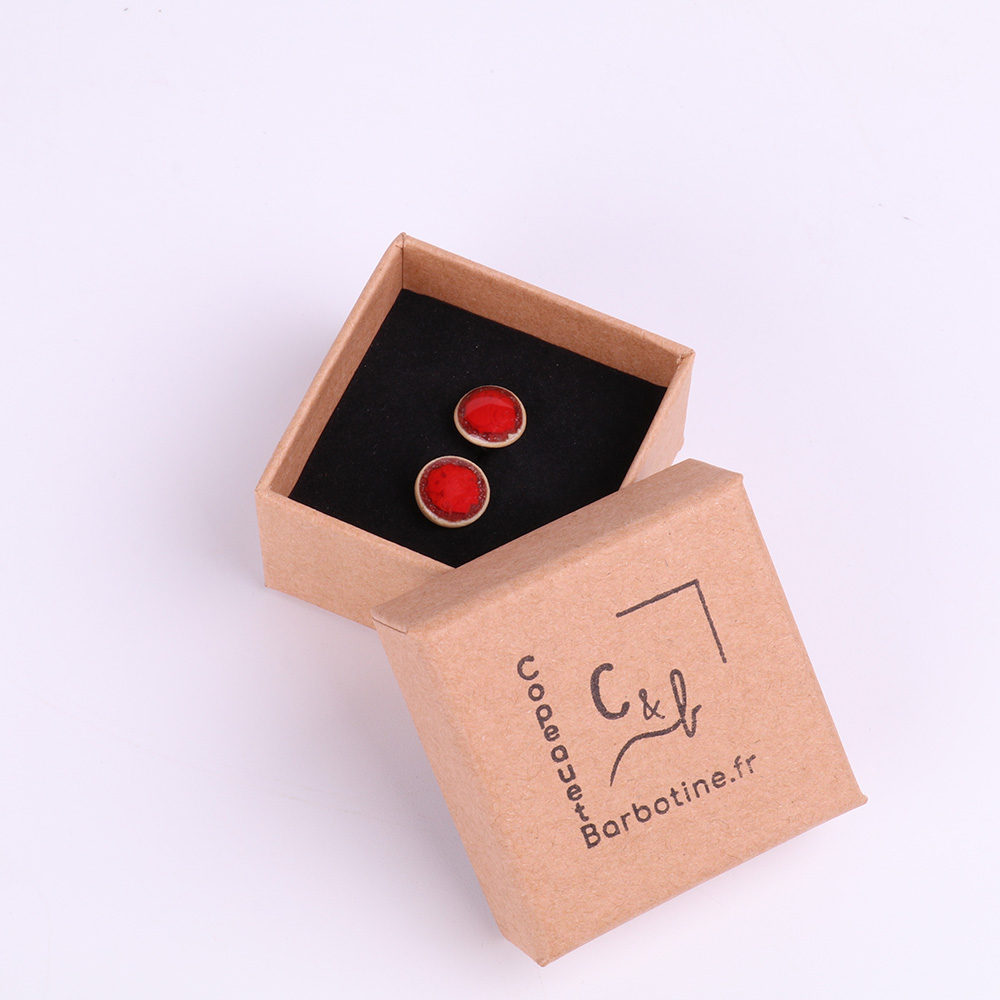 Boucles d’oreilles puce en porcelaine dans leur écrin Paire de boucles d’oreilles puce en porcelaine présentées dans une boîte kraft artisanale.