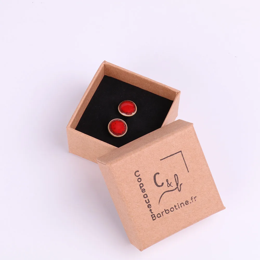 Boucles d’oreilles puce en porcelaine dans leur écrin Paire de boucles d’oreilles puce en porcelaine présentées dans une boîte kraft artisanale.