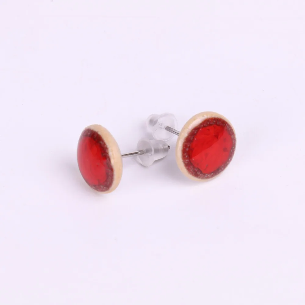 Vue rapprochée de la paire de boucles d’oreilles puce en porcelaine Rouge Feu, détail de la couleur éclatante et de l’émail artisanal.