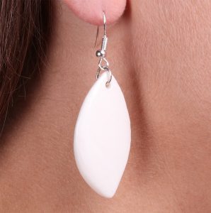 Zoom sur les boucles d’oreilles feuille en porcelaine blanche, mettant en valeur les détails artisanaux de la céramique.