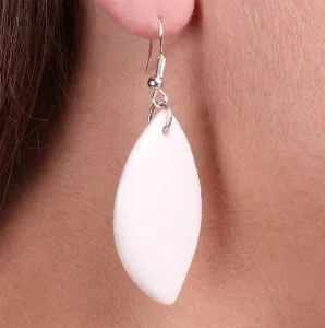Zoom sur les boucles d’oreilles feuille en porcelaine blanche, mettant en valeur les détails artisanaux de la céramique.
