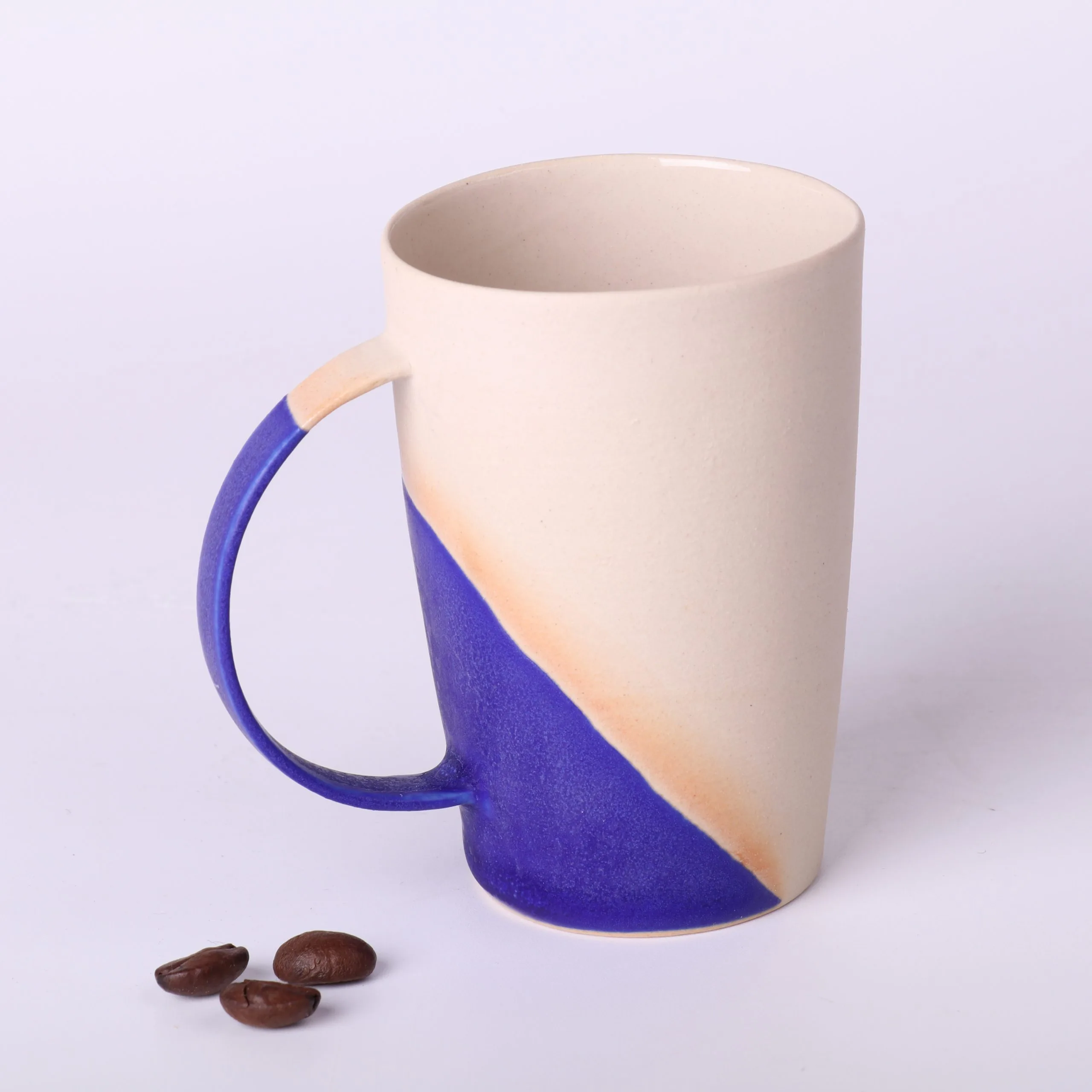 Tasse expresso design Bleu Klein — vue de face Tasse expresso design Bleu Klein en grès — vue de face avec grains de café, anse fine, finition minimaliste.