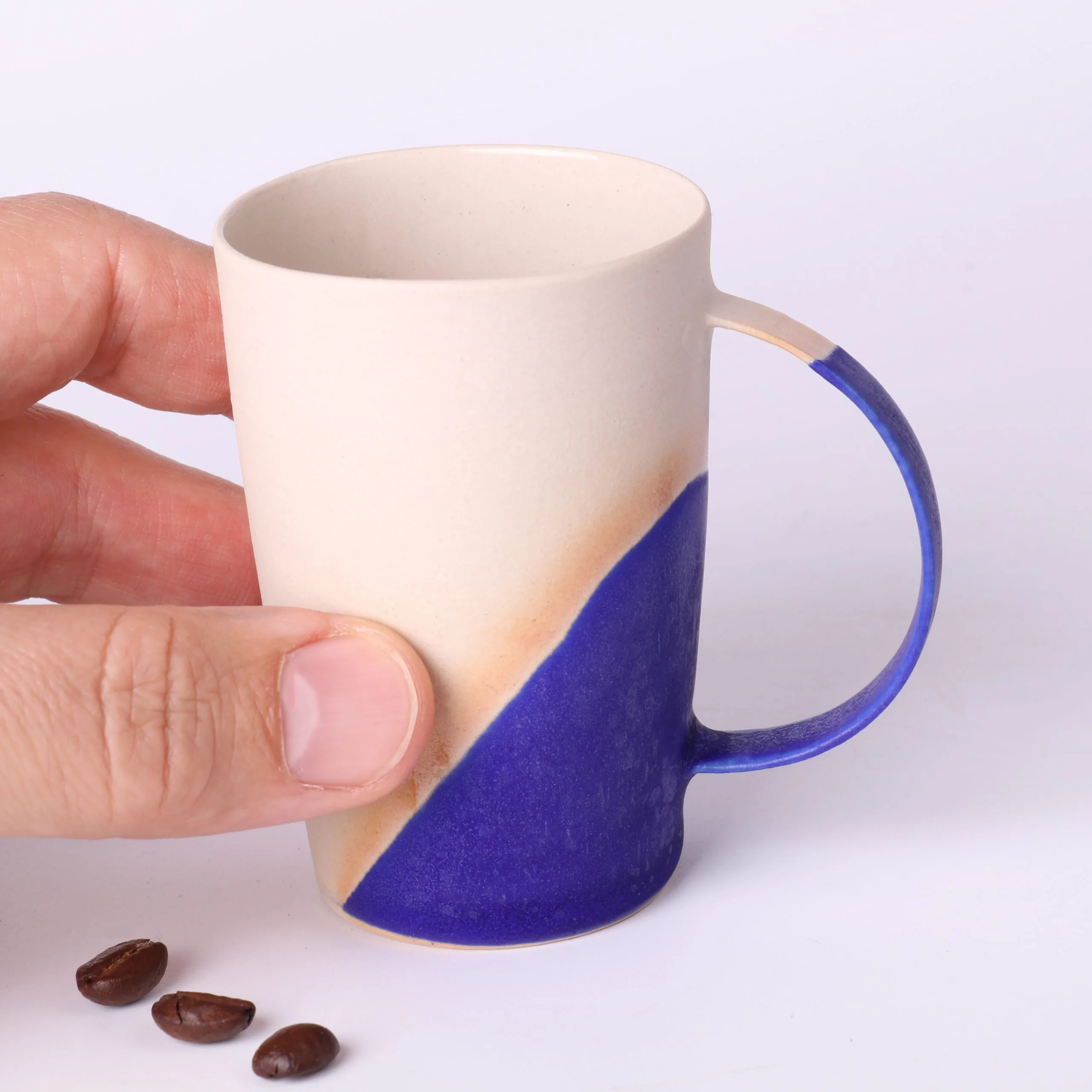 Tasse expresso design Bleu Klein — tenue en main Tasse expresso design Bleu Klein tenue en main — échelle réelle, parois fines, grès crème et émail intense.