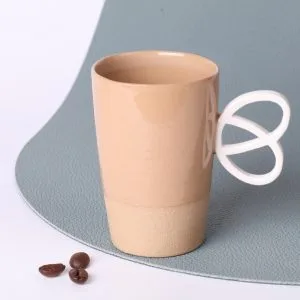 Détail de l’anse Bretzel en porcelaine sur tasse expresso en grès caramel 90 ml, faite main en Alsace.