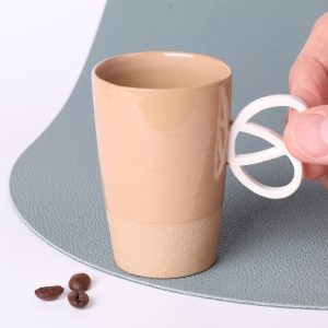 Tasse expresso artisanale Alsace en grès émaillé caramel, 90 ml, anse Bretzel en porcelaine, vue trois-quarts.