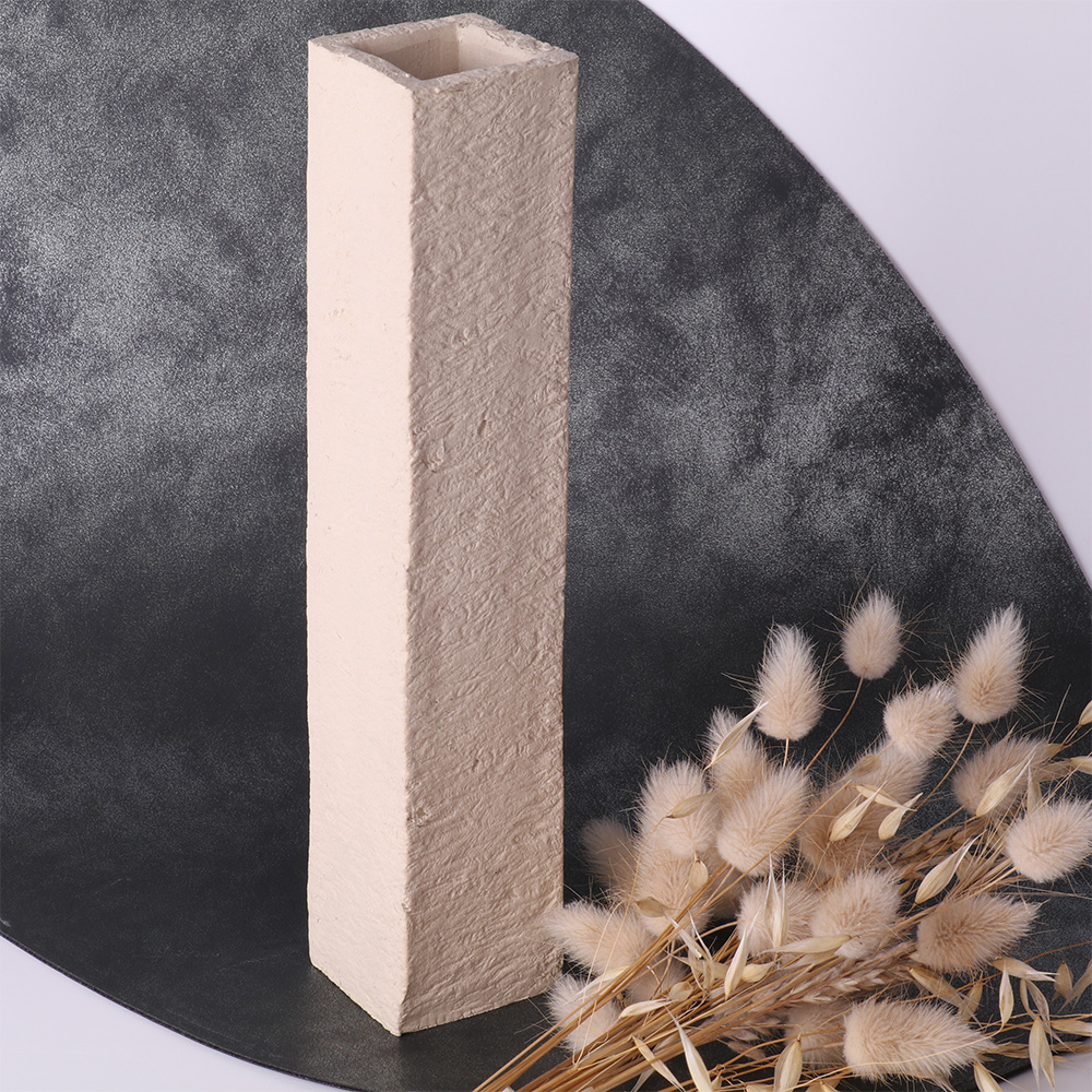 Vase rectangulaire en céramique beige avec texture brute, accompagné de fleurs séchées claires.